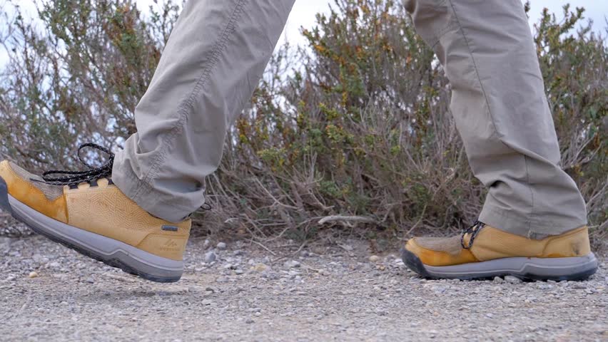 Slow motion close-up shot of a man walking along a gravel path at the Sete salt flats