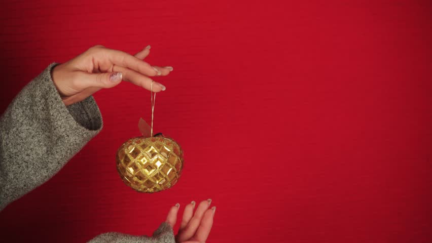 A golden Christmas ball is like a symbol of the new year and Christmas. Female hands hold a Christmas tree toy. The girl gives a festive mood. New Year symbol of the dragon. Festive atmosphere. | Shutterstock HD Video #1108925339