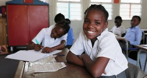 Close-up. Black African school girl smiling at camera sitting at a desk in a classroom in Africa - Powered by Shutterstock - Get 15% off with code: PIKWIZARD15