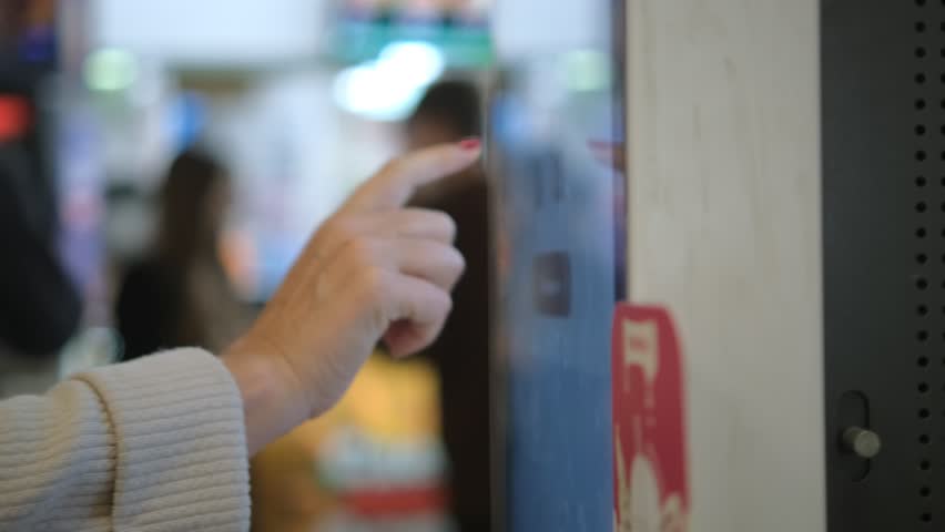 Girl using touch terminal makes a quick order through the self-service. Woman choosing dessert via self-service machine at fast food restaurant. Person swipes the screen making an order. Royalty-Free Stock Footage #1108936281