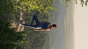 Vertical Video, Young Athletic Woman Meditating on the Top of the Mountain, Zen Yoga Meditation in Nature. Beautiful Slim Girl is Doing Spiritual Yoga Outdoors. Slow Motion.