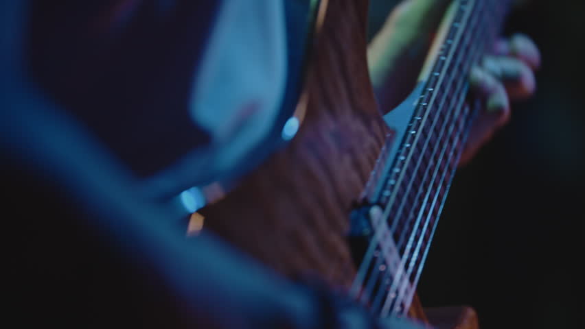 Concert rock band performing on stage, closeup of male hands playing guitar. Crowd of people listening. Music punk, heavy metal or rock group. The guitarist performs on stage. Stage light, smoke. Royalty-Free Stock Footage #1108940007