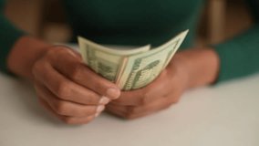 Closeup hands of unrecognizable African-American female holding and counting dollar banknotes sitting at home desk. Close-up of young woman count money cash. Concept of investment, money exchange. - Powered by Shutterstock - Get 15% off with code: PIKWIZARD15