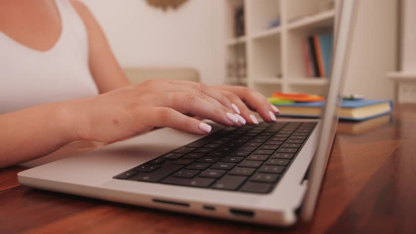 Woman typing on a keyboard laptop working at home. Modern laptop standing on the desk of the cozy home office. Royalty-Free Stock Footage #1108941711
