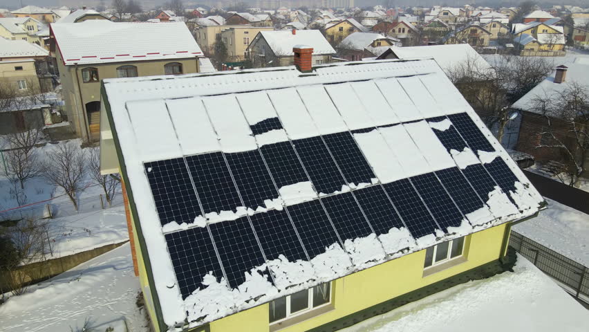 Aerial view of house roof with solar panels covered with snow melting down in winter end for producing clean energy. Concept of low effectivity of renewable electricity in northern region Royalty-Free Stock Footage #1108945317