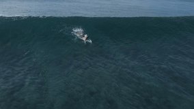 Aerial view of a surfer riding a blue wave taken at Maldives central atol. High quality 4k footage