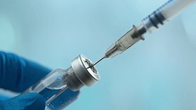 Doctor's hand holding glass vial and take injection with syringe over blue background. Vaccination or beauty therapy concept. - Powered by Shutterstock - Get 15% off with code: PIKWIZARD15