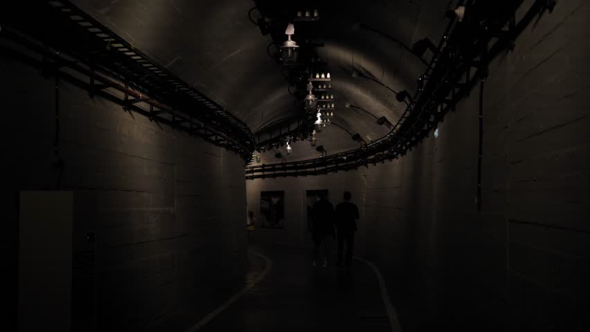 A long winding tunnel with old flashing lights and wires. Underground catacombs. Nuclear war, bomb shelters, underground tunnel.