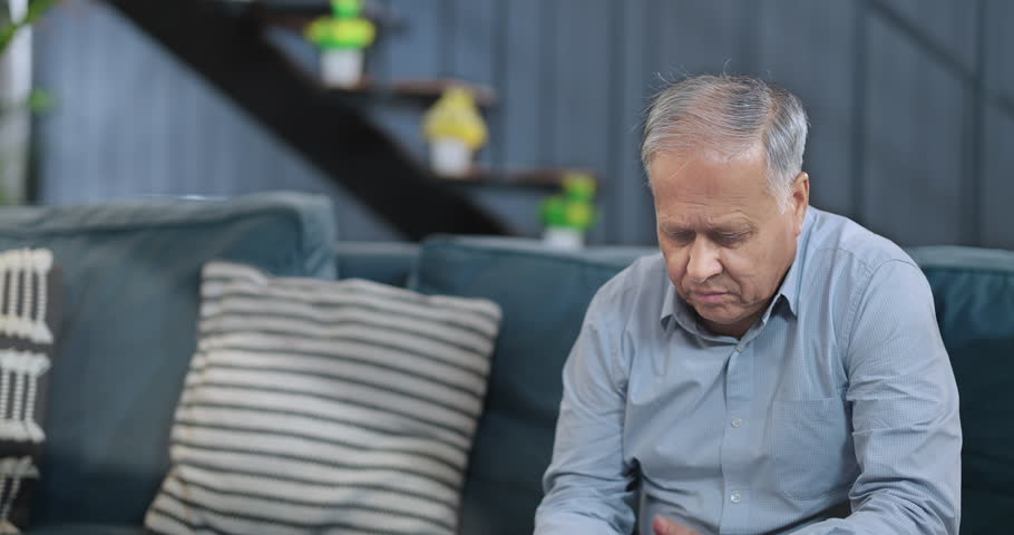 Indian unhappy retired senior man sitting alone sofa couch talking mobile phone feeling lonely indoor home. Middle aged old male grieving thinking depressed pensive suffering health problem at house Royalty-Free Stock Footage #1108959071