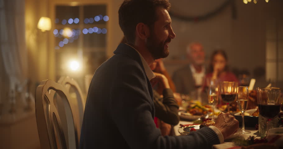 Portrait of a Diverse Group of Relatives and Friends Sitting Together Behind a Dining Table with Tasty Meals and Festive Decorations. Guests Telling Funny Stories, Creating a Joyful Holiday Mood