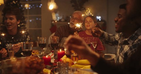 Christmas Evening Celebration at Home with Multicultural Group of Loved Ones Enjoying a Turkey Dinner. Old and Young Family Members Singing Festive Songs to Celebrate the Occasion Vídeo Stock