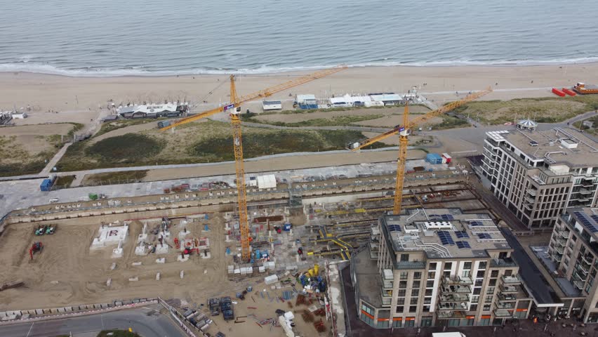 Aerial shot of construction area in Kijkduin in The Hague next to the coast, Drone shot moving around the construction site with a view on the beach | Shutterstock HD Video #1108966103