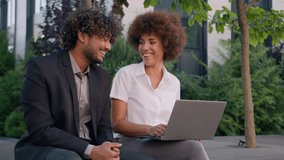 Two diverse multiracial multiethnic business colleagues partners workers employers coworkers sit in city downtown outdoors together with computer laptop support talking discuss online task project - Powered by Shutterstock - Get 15% off with code: PIKWIZARD15