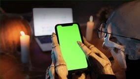 Skeleton online touch bone fingers of cell phone with chromakey chatting, flipping through the video platform and chatting in social networks. Halloween party celebration. - Powered by Shutterstock - Get 15% off with code: PIKWIZARD15
