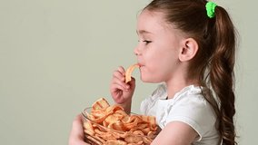 A girl takes chips snacks with lard from a bowl and eats them, portrait on a white background and copy space.