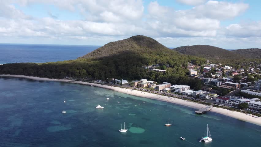 Aerial view of an Australian coastline with parked sailing boats and a mountain next to a coastal town