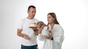 Caucasian family celebrating first month of their parenting. Woman waving a baby and man holding a cake.
