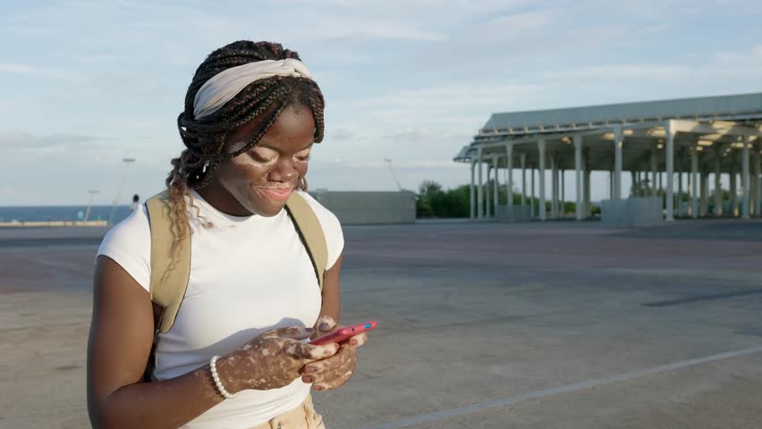 Happy millennial black girl having fun chatting on smartphone device while walking outdoors. Youth culture and technology concept. | Shutterstock HD Video #1108992389