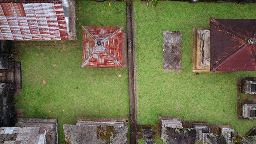 Top-down view of small Hindu temple at outskirts of Balinese village, camera fly up and reveal surroundings. Lush tropical forest seen at one side, rice plantations at other side of religious compound | Shutterstock HD Video #1108992631