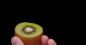 Video of hollowing out a kiwifruit with a spoon.
Black background.