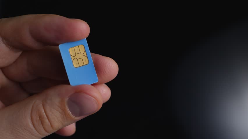 Hand hold blue mini SIM card on black background. Communication equipment. 5g network and technology, smartphone service concept. Integrated circuit with chip and connections - Powered by Shutterstock - Get 15% off with code: PIKWIZARD15