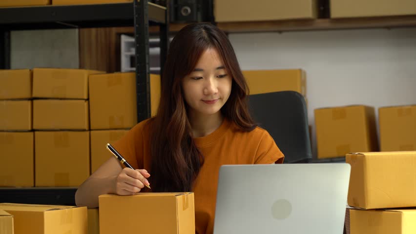 Shipping shopping online ,woman start up small business owner writing address on cardboard box at workplace.small business entrepreneur SME or freelance asian woman working with box at home. | Shutterstock HD Video #1108995059