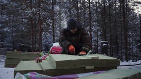 Men cutting building materials in winter forest. Clip. Man cuts materials for building house in forest in winter. Man prepares materials for building house in forest - Powered by Shutterstock - Get 15% off with code: PIKWIZARD15