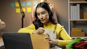SME owner and Startup small business entrepreneur.Young Asian women using a laptop and packing with box Cheerful success.SME owner Asia people young woman record video,live streaming online at shop.
