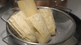 This video shows hands places tamales in a pot steamer.