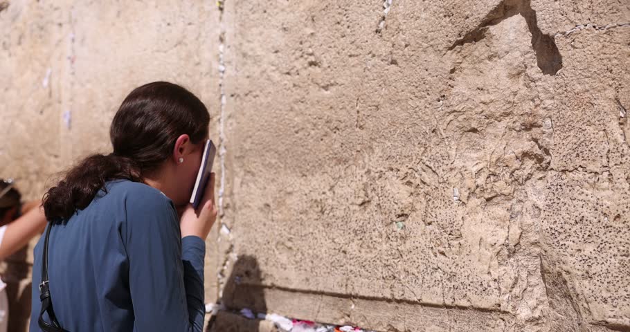 Jewish Girl praying. Orthodox Jew facing the Western wall while praying. Other religious women in background pray to the Kotel. Wailing wall Jerusalem, Jerusalem, Israel. God's religion and conflict Royalty-Free Stock Footage #1109003841
