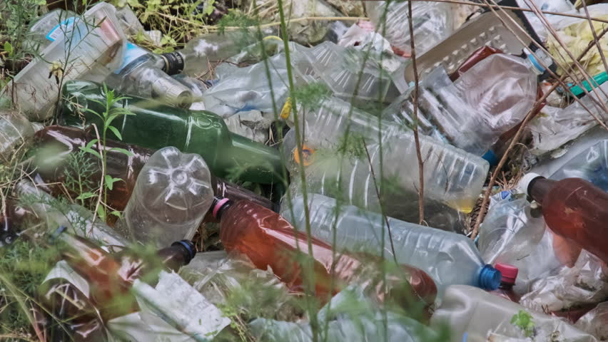 Garbage dump of plastic and bottles in the forest. Pile of synthetic waste in nature, environment problems. Illegal rubbish dump on the ground. Lot of trash throwed in forest pit. Ecological disaster | Shutterstock HD Video #1109007517
