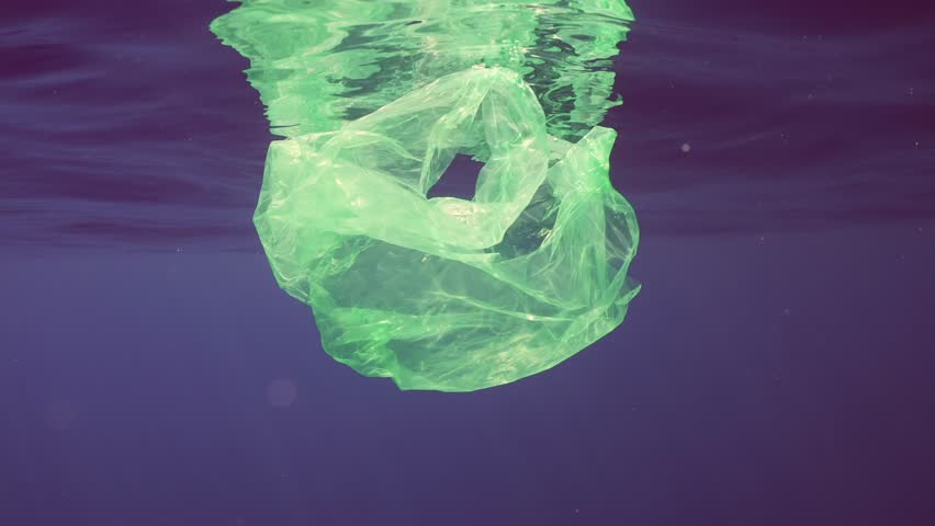 Discarded disposable green plastic bag drifts slowly under waves reflected on surface of Mediterranean sea in bright sun rays, Slow motion, Underwater shot. Plastic pollution of Ocean | Shutterstock HD Video #1109009067