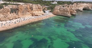 Drone video over Algarve cliffs near Praia do Marinha beach during daytime in summer