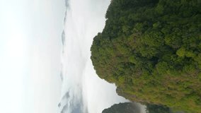 Vertical video. Aerial view of cloud-covered mountains and dense rainforests in Khao Sok, Thailand.