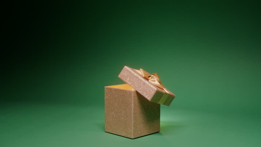 Magical night background with elegant glittery golden gift box with open cover and light seen inside. Christmas scene on green background, copy space slow motion RED camera. Merry Christmas, 2024 year