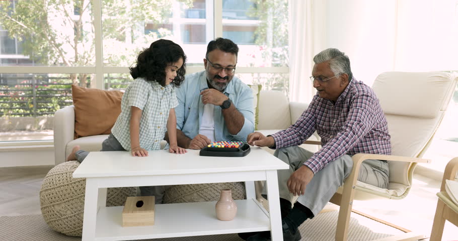 Happy multigenerational Indian men, grandchild, granddad, great-granddad play cool modern rainbow balls boardgame give high five celebrate victory spend carefree leisure together at home. Family fun Royalty-Free Stock Footage #1109028157