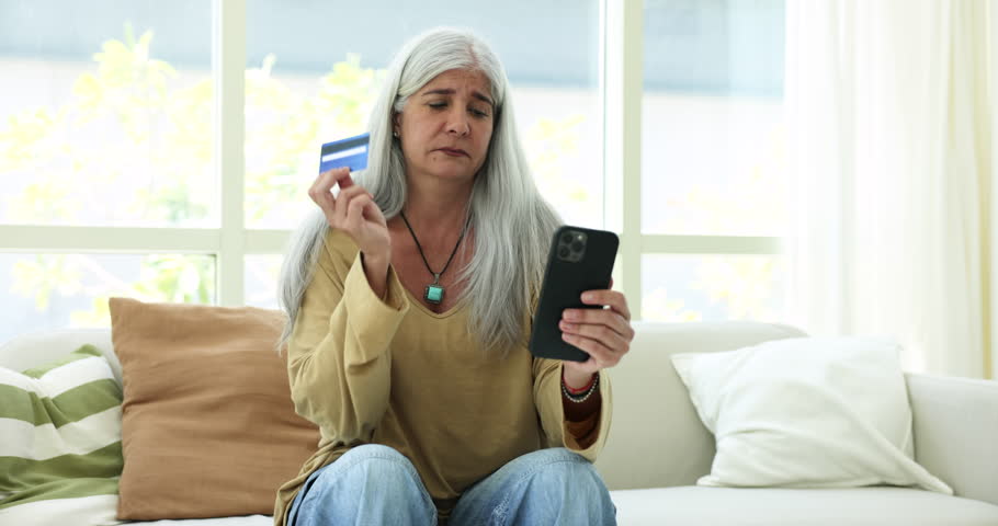 Aged woman holds phone and card have problems with e-bank services feel concerned, use modern app, check balance, tries to pay online, looks upset due to unsuccessful electronic payment. Fraud, scam | Shutterstock HD Video #1109028163