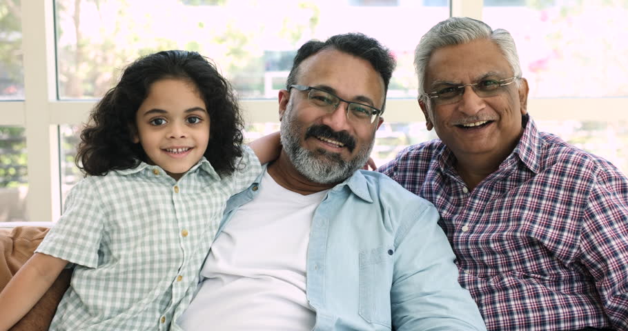 Close up portrait of happy Indian little boy, mature grandfather and old great-grandfather. Multi-generational family resting on couch smile look at camera, feeling love, showing protection and care Royalty-Free Stock Footage #1109028175