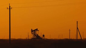 Pumping petroleum Rig in desert at sunset. Oil industry. Pump Jack Extracting Crude Oil from a Oil Well. Fossil Fuel Energy. Working oil pump jacks. slow motion video.