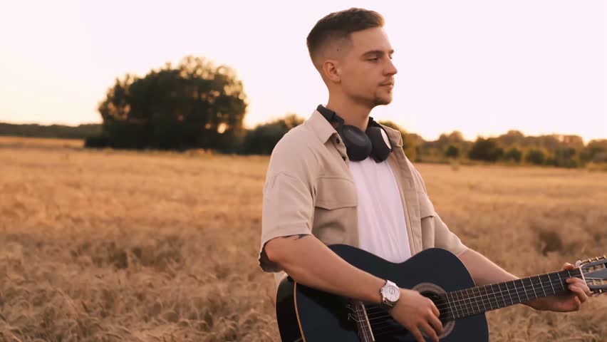 Man playing guitar outdoors, traveler on rest stop, hiking, playing acoustic guitar