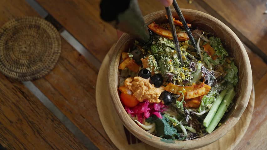  Poke bowl with avocado, edamame, cucumber on a wooden plate. Healthy food. Organic eating. Olives, sesame seeds, Nori seaweed, herbs, Beets, on diet lunch. Balinese food, view from above