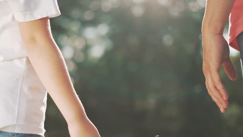 happy family father and daughter hold hands close up. Dad and baby girl hands together at sunset. Father Day. Dad and daughter are holding hands. A father extended a helping hand to his daughter child