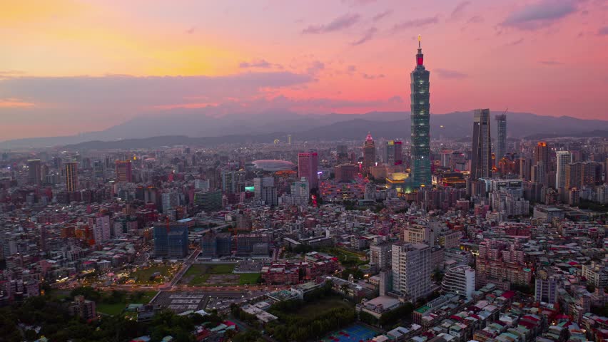 Aerial hyperlapse above Downtown Taipei, vibrant capital of Taiwan, with 101 Tower standing out amid modern skyscrapers at dusk in XinYi Commercial District and city lights dazzling under twilight sky