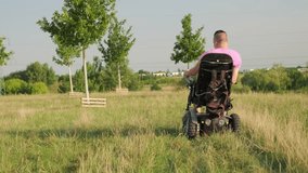 Man in wheelchair during leisurely stroll in green meadow illuminated by bright sunlight. Person with leg injury after car accident watches nature in park - Powered by Shutterstock - Get 15% off with code: PIKWIZARD15