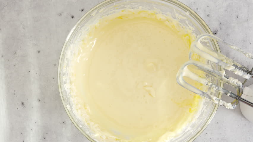 Cream cheese, eggs, corn starch, and sugar in a bowl. Cheesecake recipe, mixing ingredients in a glass bowl