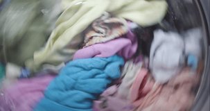 Washing laundry machine at home washing dirty colorful clothes and fabrics. Abstract closeup video.