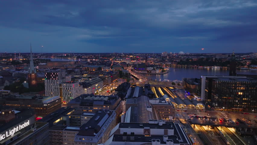Forwards fly above modern buildings in urban borough around Central station. Main train station a road transport infrastructure at dusk. Stockholm, Sweden Royalty-Free Stock Footage #1109050011
