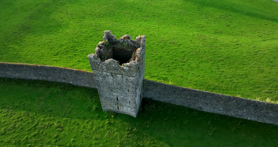Medieval defence wall with tower against a green field 4k