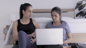 young asian women using laptop watching workouts online together 