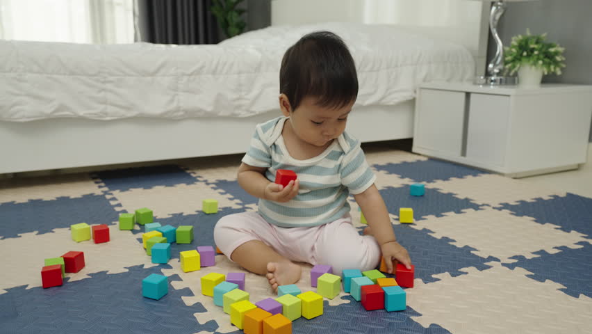 infant baby biting wooden block toy on jigsaw mat in the bedroom Royalty-Free Stock Footage #1109051987